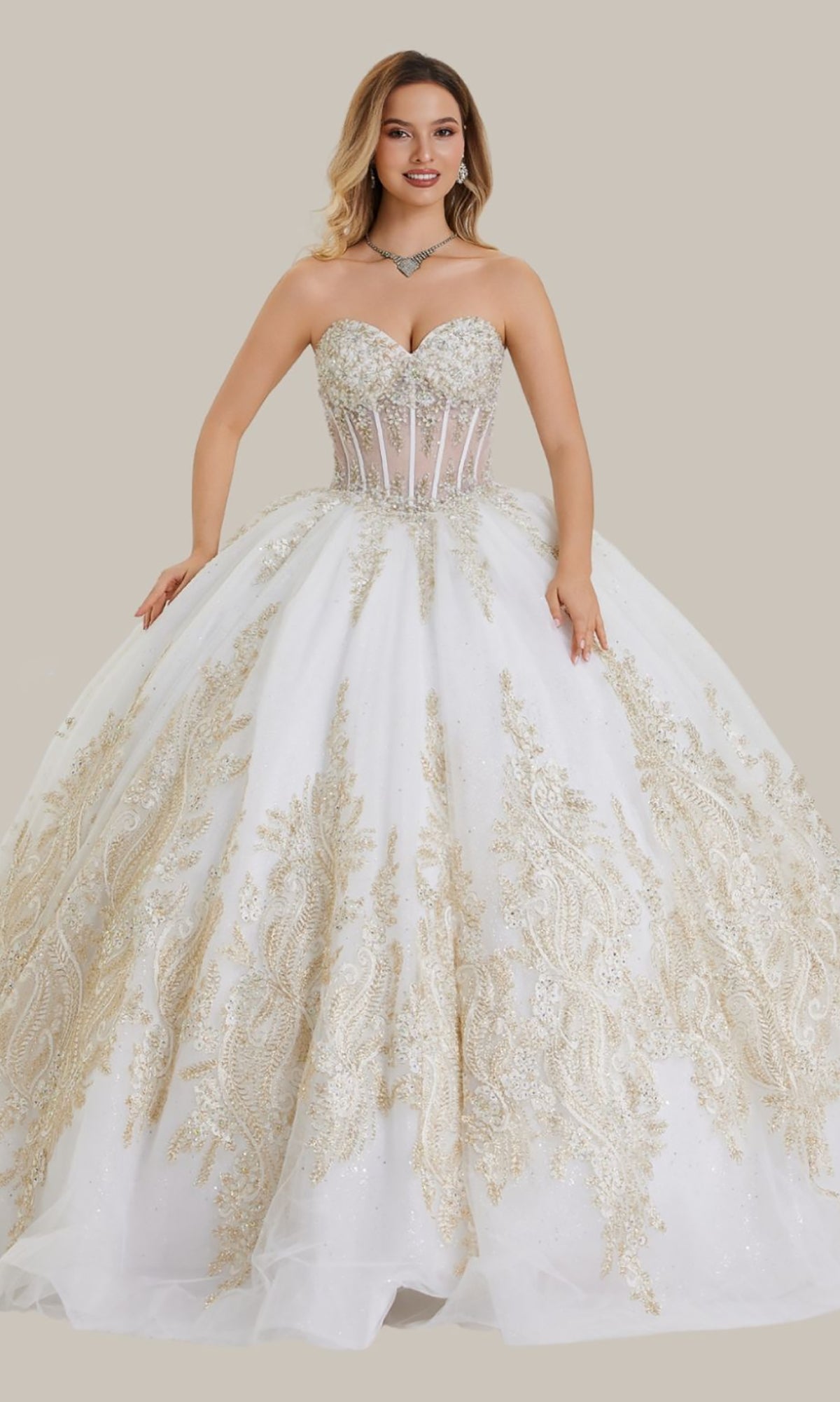 A woman wearing the Quinceanera Dress 26405 by Stella Couture in ivory, featuring a strapless design with a sheer corset bodice and a full skirt adorned with intricate gold embellishments and delicate beading.